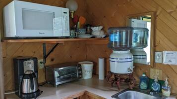 A compact kitchen with a microwave, toaster, coffee maker, and a sink.