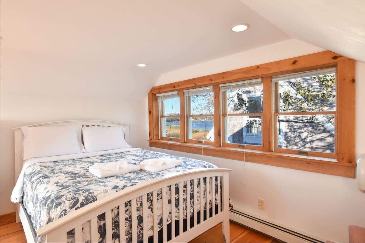 A bedroom with a bed, a crib, and a large window with a view of the outside.