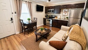 A compact living space with a kitchenette, a dining area, and a seating area with a sofa and coffee table. - Modern 1BR Retreat Full Kitchen Walkable Free Parking Apt B (Houston)