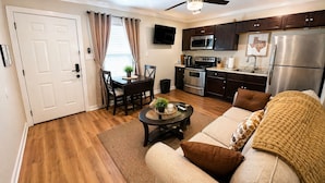 A modern kitchen with dark cabinets, stainless steel appliances, and a dining area with a table and chairs. - Modern 1BR Retreat Full Kitchen Walkable Free Parking Apt B (Houston)