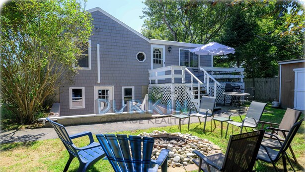 A backyard with a barbecue area, outdoor seating, and a house with a deck. - Short drive of just over 1 mile to Scarborough State Beach (Narragansett)