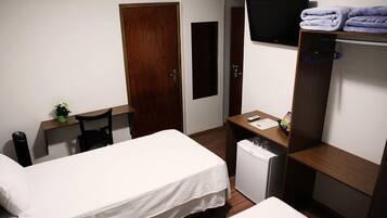 Habitación de hotel con dos camas, un escritorio, televisión, refrigerador pequeño y armario.