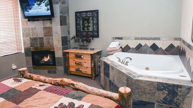 Ein Schlafzimmer mit einem großen Bett, Kamin, Fernseher und einer Badewanne.