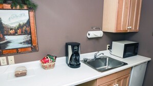 Eine kleine Küchenzeile mit Kaffeemaschine, Mikrowelle und Spüle.