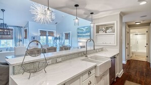A modern kitchen with a large island, white cabinetry, and a backsplash. - Treetop Escape Loft - Close to Shopping & Dining, Free Bikes/Fitness/Tennis (Rosemary Beach)
