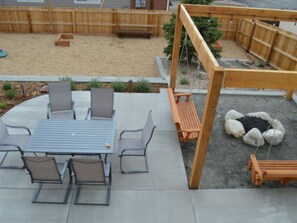 A patio with a table and chairs, a swing set, and a sandbox.