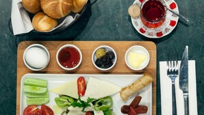Una bandeja de madera con pan, salsas, queso y verduras.