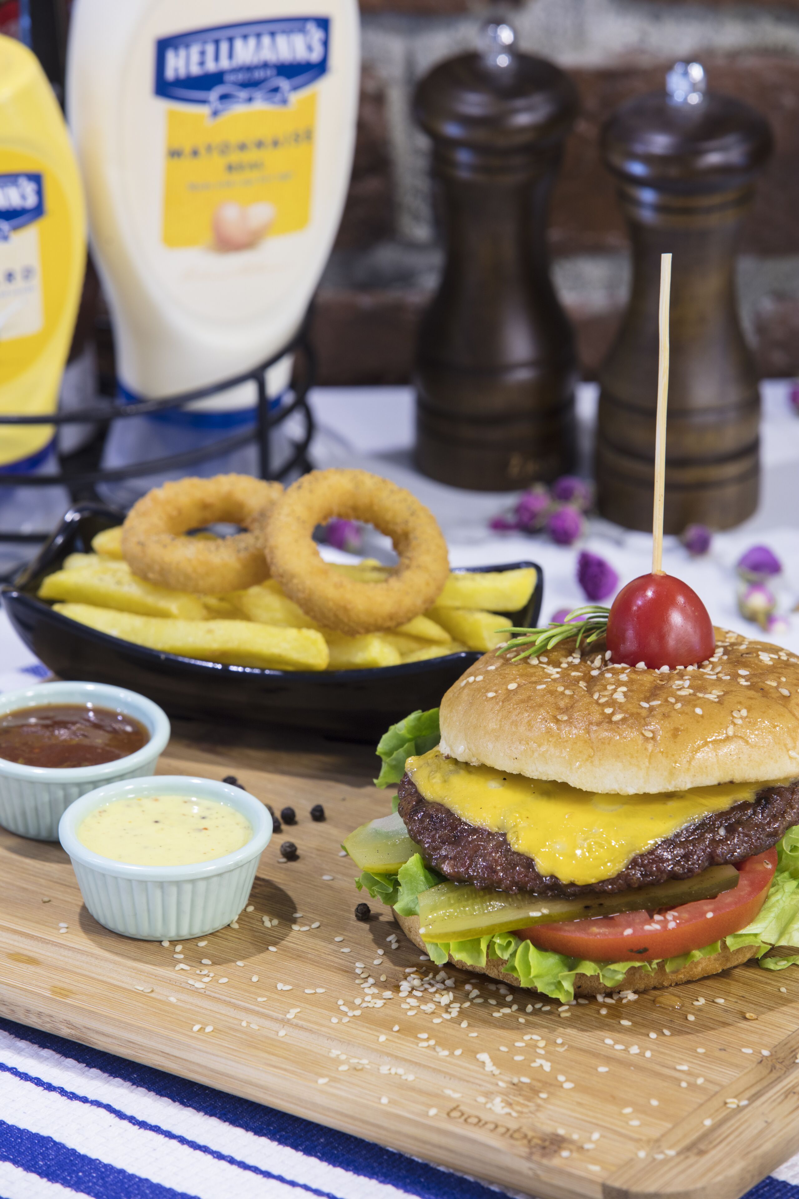 A meal with a burger, fries, and onion rings, accompanied by condiments.