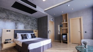 Una habitación de hotel moderna con una cama grande, mesitas de noche, un escritorio y una silla.