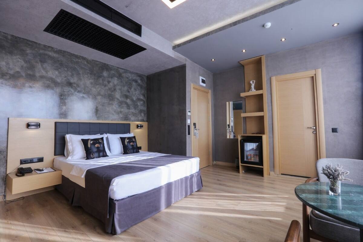 A modern hotel room with a large bed, bedside tables, a desk, and a chair.