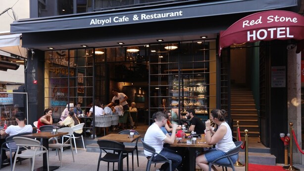 Un área de estar al aire libre del Café y Restaurante Altiyol, con mesas y sillas, y un letrero del Hotel Red Stone al fondo.