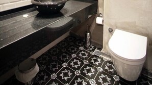 Un baño moderno con piso de baldosas en blanco y negro, un lavamanos redondo y un inodoro.