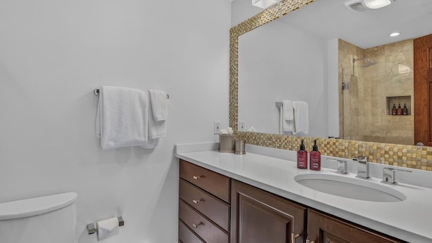 A modern bathroom with a white sink, wooden cabinets, and a large mirror. - Ski-in/Ski-out + Hot Tub + Luxury | Chalet Premio (Beaver Creek)