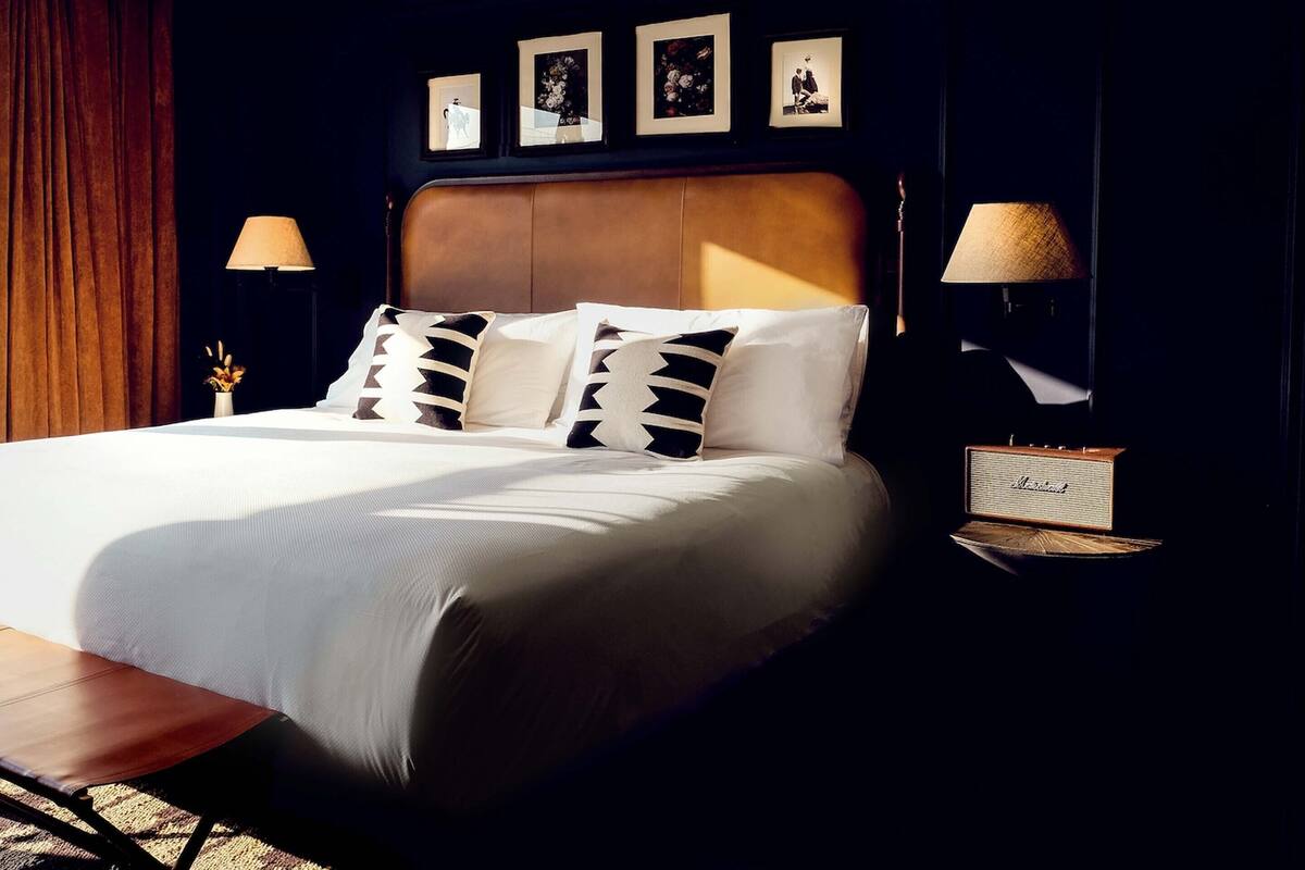 A neatly made bed with a headboard, two bedside lamps, and a small table with a lamp.