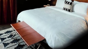 Une chambre d’hôtel moderne avec un grand lit, une lucarne et un banc en bois.
