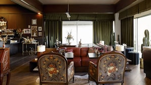 Un salon chaleureux avec un canapé en cuir, des fauteuils à motifs, une table basse et un coin bar doté d’un comptoir et d’étagères.