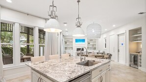 A spacious kitchen with a large island, white cabinetry, and pendant lighting.