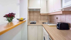 A compact kitchen with a gas stove, sink, and a toaster.