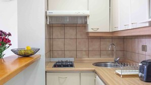 A compact kitchen with a built-in washing machine, a sink, and a stove.