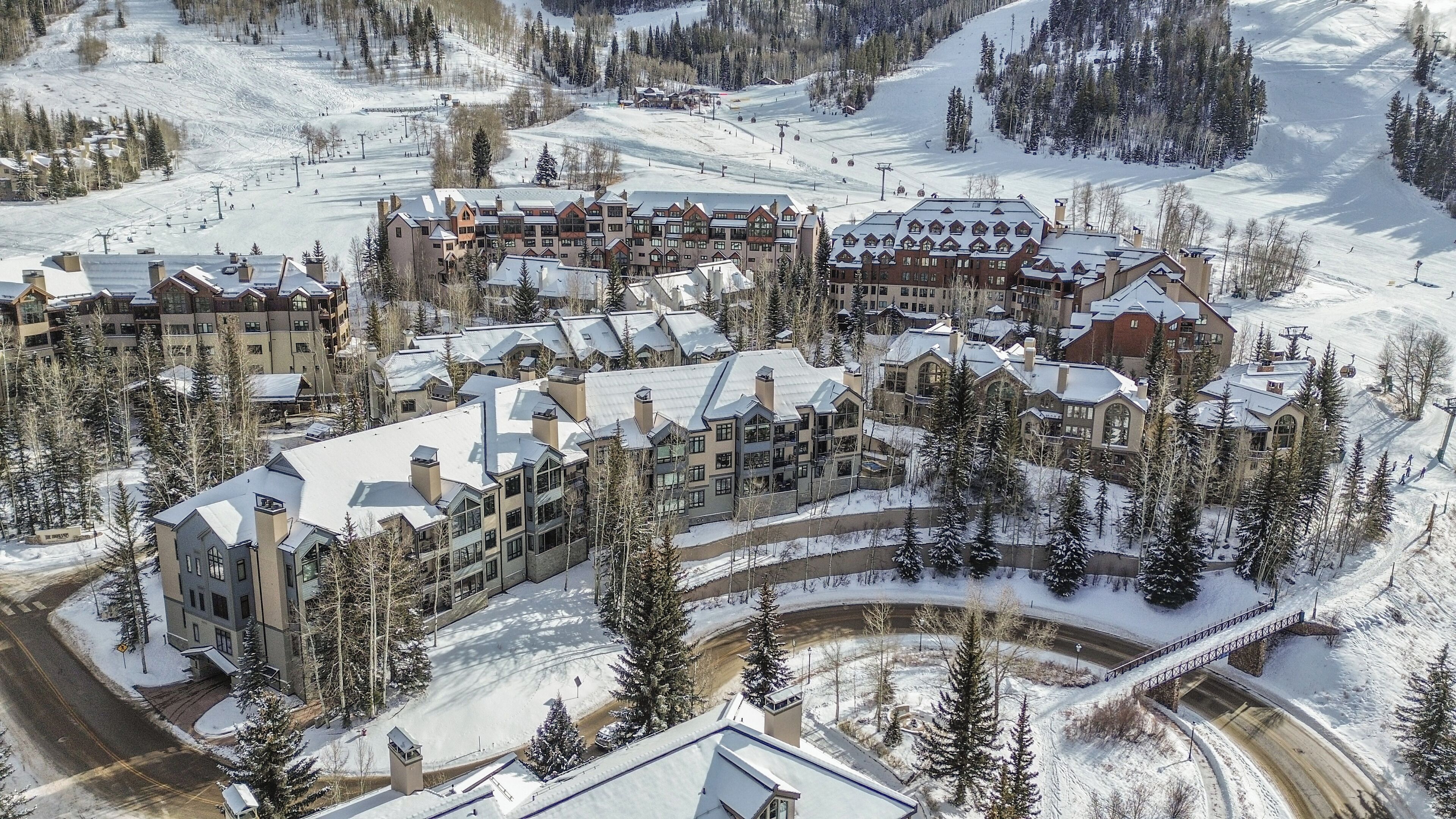 A snow-covered resort with multiple buildings, ski slopes, and a ski lift.