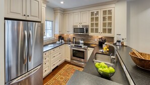 A modern kitchen with stainless steel appliances, a large island, and a stone backsplash.
