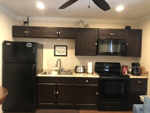 Enjoy cooking in this well-equipped kitchen with a refrigerator, microwave, stove, and sink.