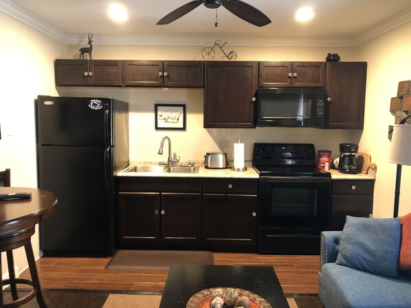 Enjoy cooking in the fully equipped kitchen with a stove, microwave, and refrigerator. Relax in the adjacent living area with a dining table and comfortable couch.