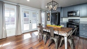 A kitchen with a wooden table, chairs, a chandelier, and modern appliances. - Downtown Bungalow by Mountain Oasis | Walking Distance to Downtown Square (Ellijay)