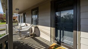 A covered porch with wicker furniture and a sliding glass door. - Downtown Bungalow by Mountain Oasis | Walking Distance to Downtown Square (Ellijay)