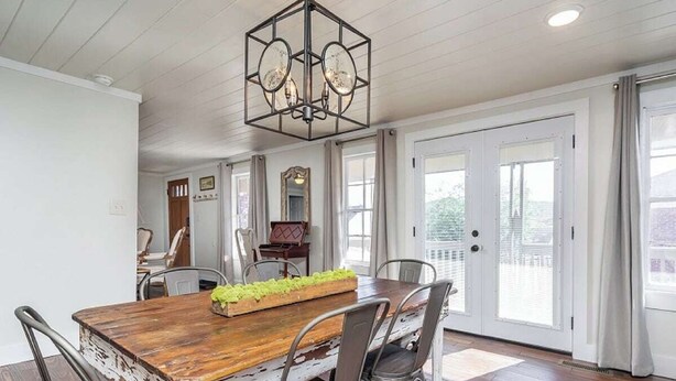 A dining area with a rustic wooden table, metal chairs, and a chandelier. - Downtown Bungalow by Mountain Oasis | Walking Distance to Downtown Square (Ellijay)