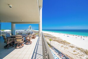 Een balkon met buitenmeubilair met uitzicht op een strand.