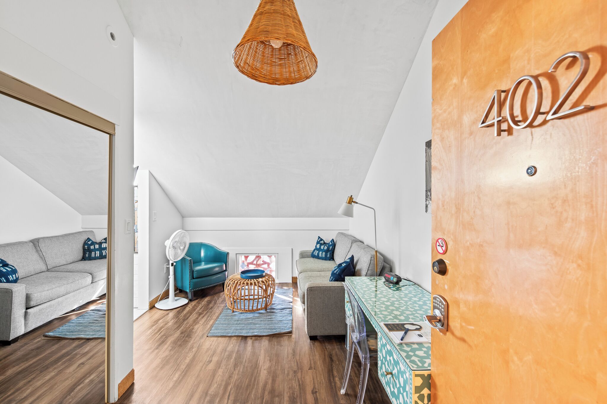 Una sala de estar moderna con un sofá, un sillón color aguamarina, una mesita y una lámpara de pie de mimbre.