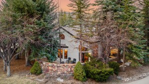 A house surrounded by trees with a stone wall in front.