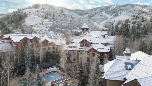 A resort with multiple buildings, a pool area, and a mountainous backdrop.