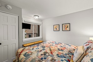 Ein Schlafzimmer mit einem Bett, einem Fenster, einer Tür und zwei gerahmten Bildern an der Wand.