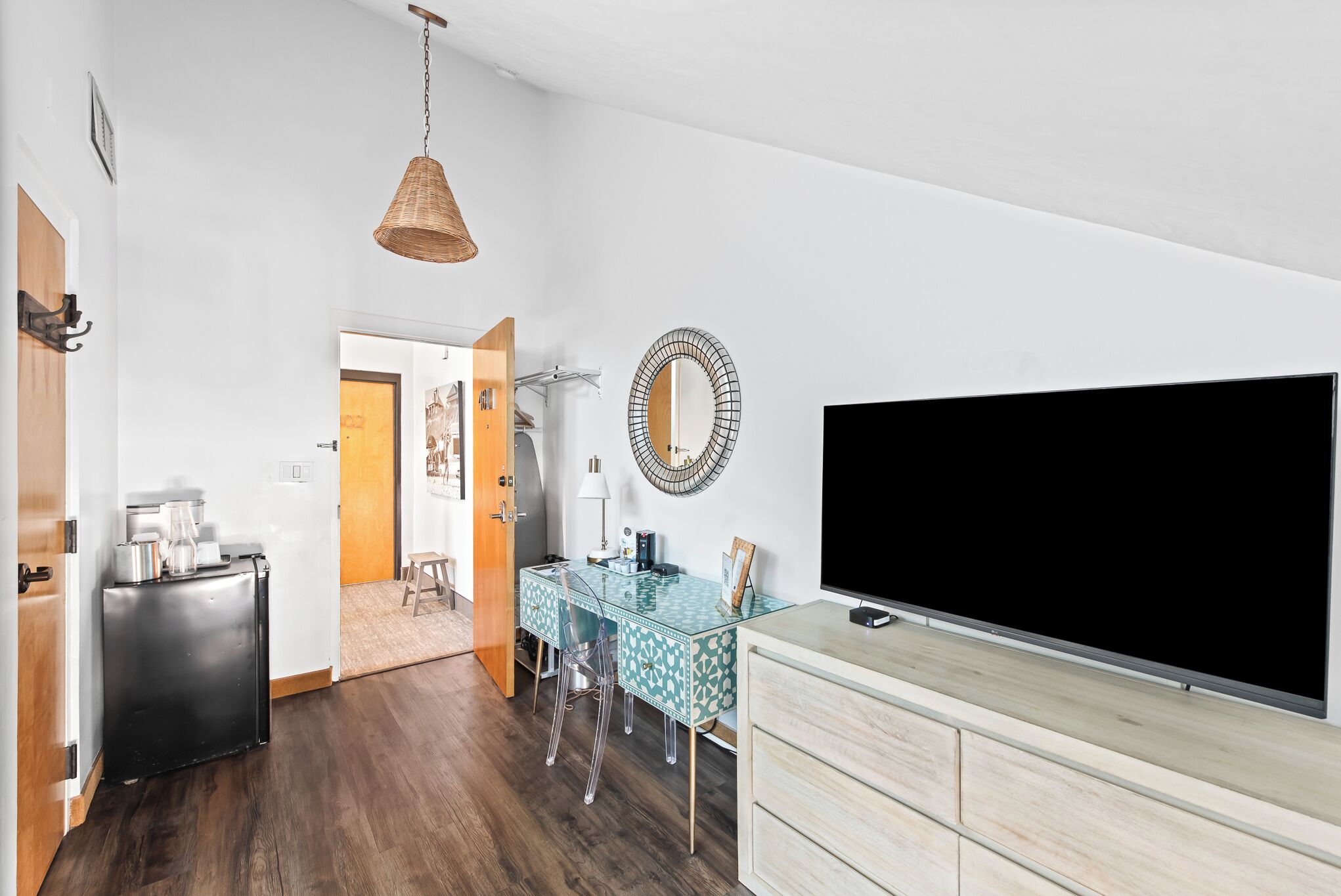 A modern living room with a TV, a dining table, and a kitchen area.