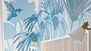 Une chambre à coucher avec un lit, des oreillers, une table de chevet, une lampe et une fresque murale.