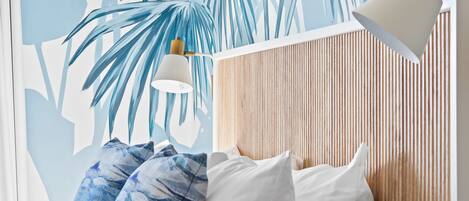 Ein Schlafzimmer mit einem Bett, Kissen, einem Nachttisch, einer Lampe und Wandbild.