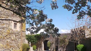 A stone building with a small window, surrounded by a well-maintained lawn and flowering trees. - Majestic 17th-century castle in stunning Somerset countryside. Pet friendly. (Clevedon)