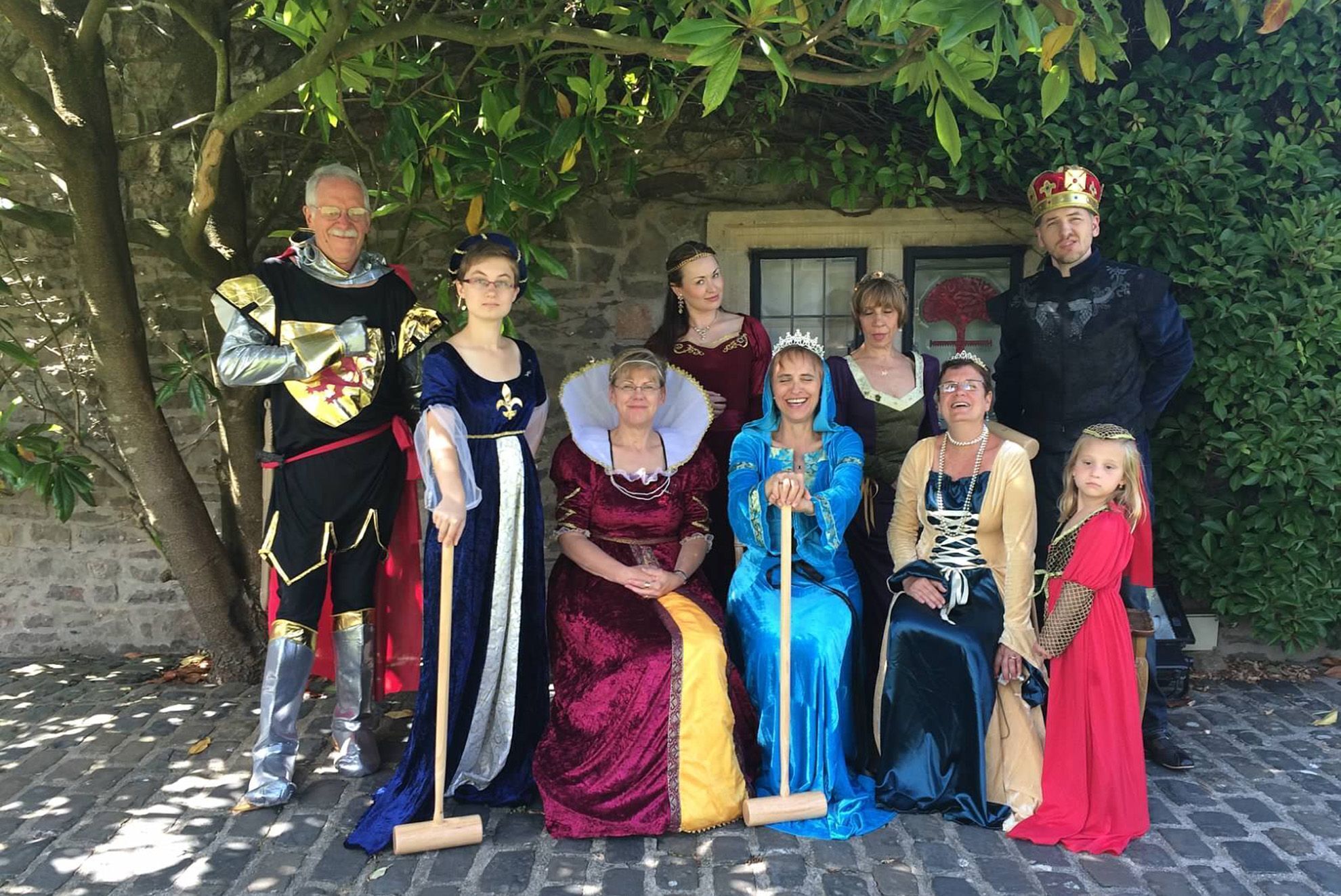 Un grupo de personas vestidas con trajes históricos posando frente a un edificio de piedra con una ventana y una puerta.