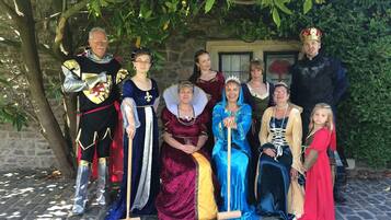 Un grupo de personas vestidas con trajes históricos posando frente a un edificio de piedra con una ventana y una puerta.