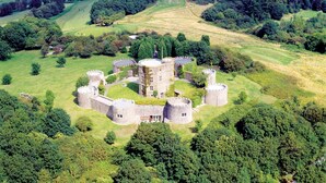 An aerial view of a historic castle surrounded by lush greenery and rolling hills. - Majestic 17th-century castle in stunning Somerset countryside. Pet friendly. (Clevedon)