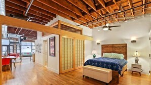 Un dormitorio con techo de madera, una cama con colcha azul, una mesita de noche y un tocador.