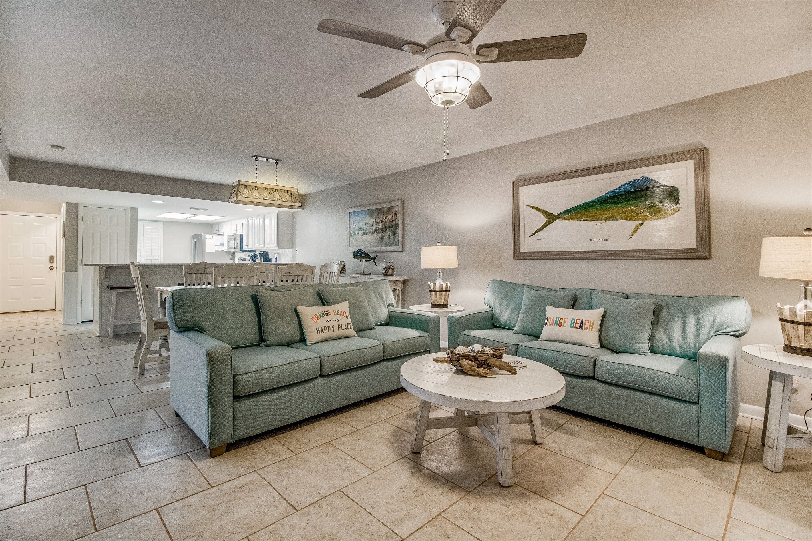 A living room with a green sofa, a round coffee table, and a ceiling fan.