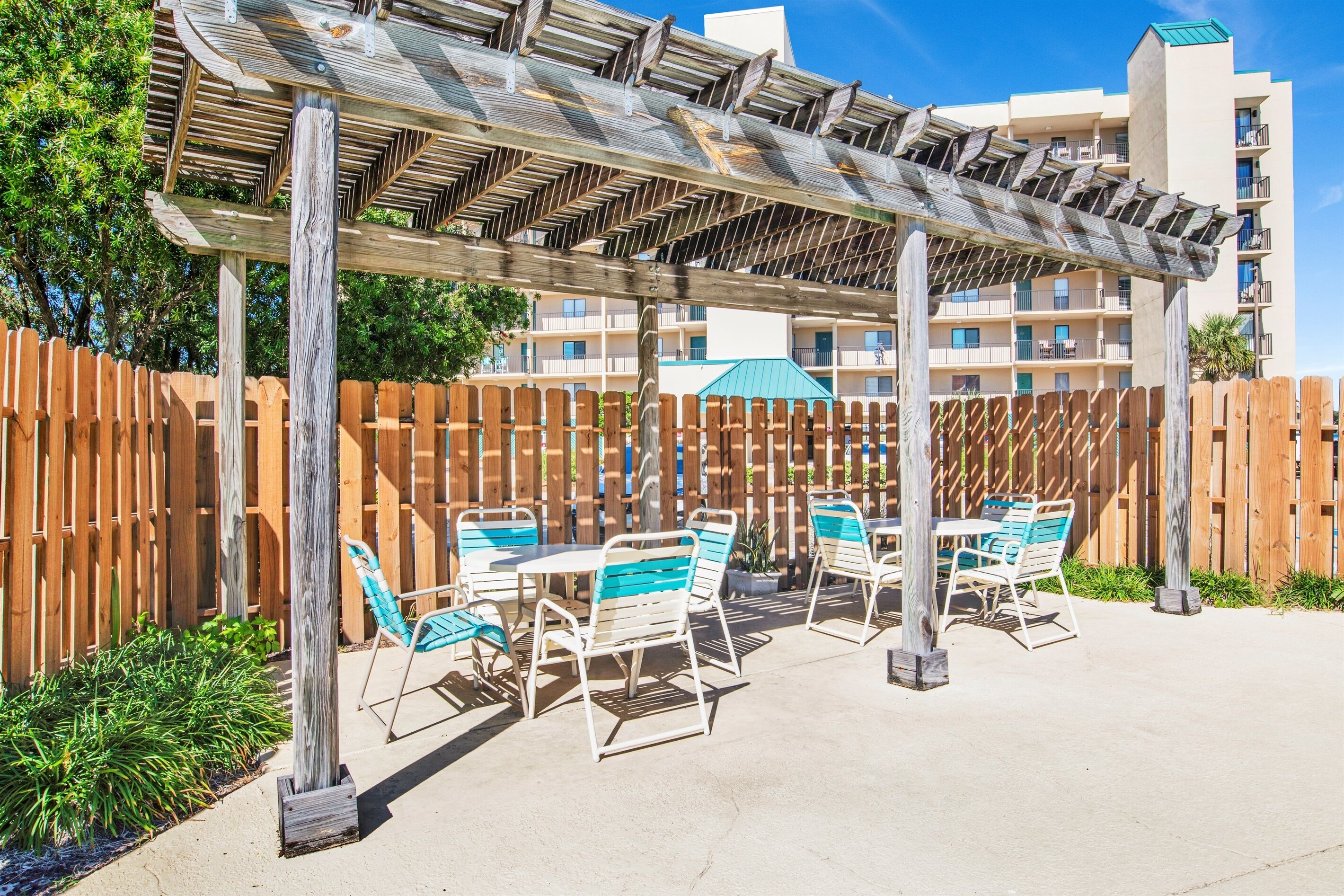 Eine Außenpatio-Terrasse mit Holz-Pergola, Tischen und Stühlen.