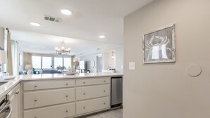 A modern kitchen with a large island, white cabinetry, and a chandelier. - Orange Beach Gulf-Front 3BR • Sleeps 10 • Bunk Room • Games • Oversized Balcony (Orange Beach)