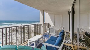 A balcony with a view of the beach, white furniture, and patterned flooring. - Orange Beach Gulf-Front 3BR • Sleeps 10 • Bunk Room • Games • Oversized Balcony (Orange Beach)