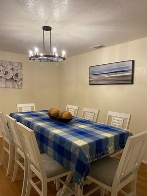 A dining area with a blue and white checkered tablecloth, a chandelier, white chairs, and a bowl of bread on the table. - Very comfortable house (1900 sqft), near airport, 281 and 1604. 4b/2ba 8 guests (San Antonio)