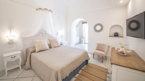 A bedroom with a large bed, bedside tables, a chair, a TV, and a mirror on the wall. - Villa dei Lecci Blu - luxury villa with terrace on the sea (Forio)
