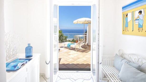 A room with a view of the sea, a white sofa, a blue vase, and a painting on the wall. - Villa dei Lecci Blu - luxury villa with terrace on the sea (Forio)